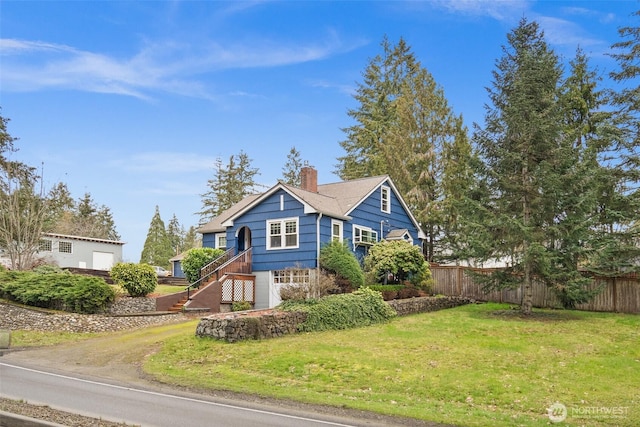 view of front of home featuring a garage, a chimney, a front yard, and fence