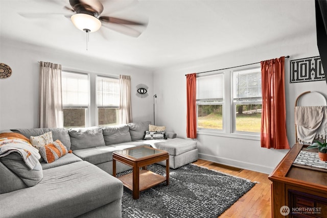 living area featuring a ceiling fan, baseboards, visible vents, and hardwood / wood-style floors