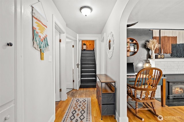 corridor featuring arched walkways, stairway, and light wood-type flooring