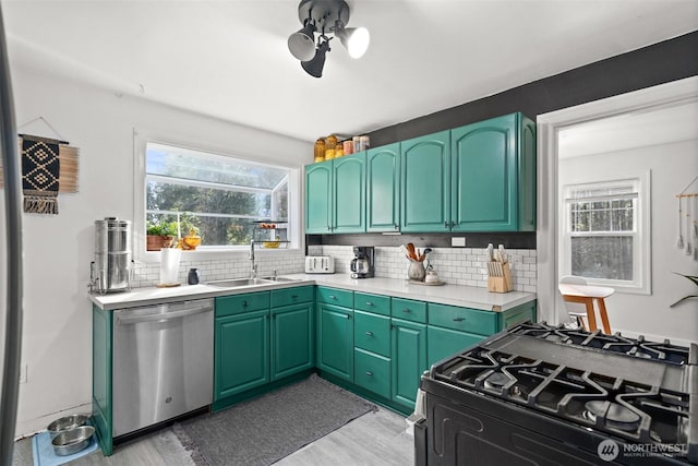 kitchen with tasteful backsplash, dishwasher, light countertops, a sink, and gas stove