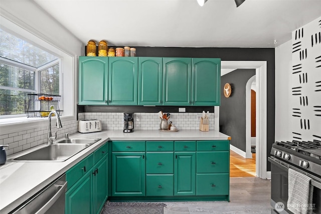 kitchen featuring arched walkways, backsplash, a sink, stainless steel dishwasher, and gas stove