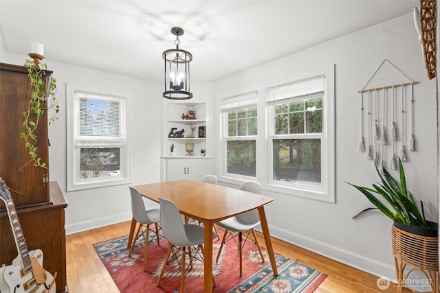 dining area with baseboards, an inviting chandelier, and light wood-style floors