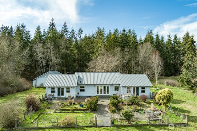 rear view of property with a yard, a standing seam roof, a gate, metal roof, and fence private yard