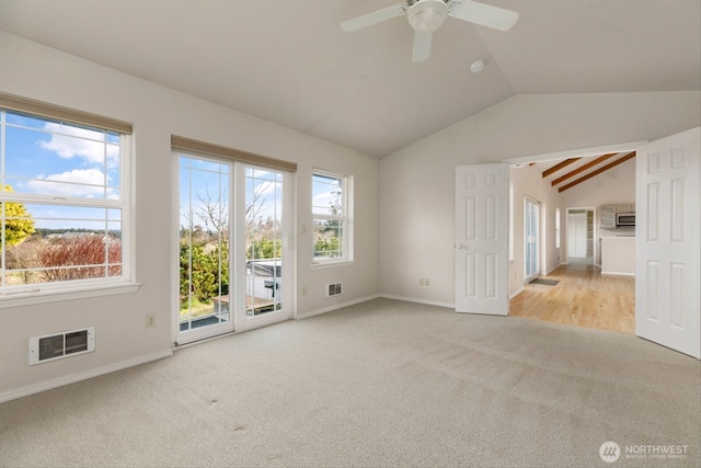 carpeted empty room featuring lofted ceiling, baseboards, and visible vents