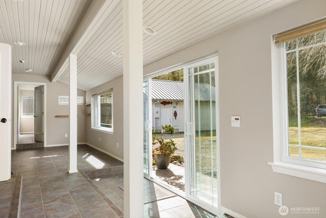 doorway featuring lofted ceiling with beams, wooden ceiling, and baseboards