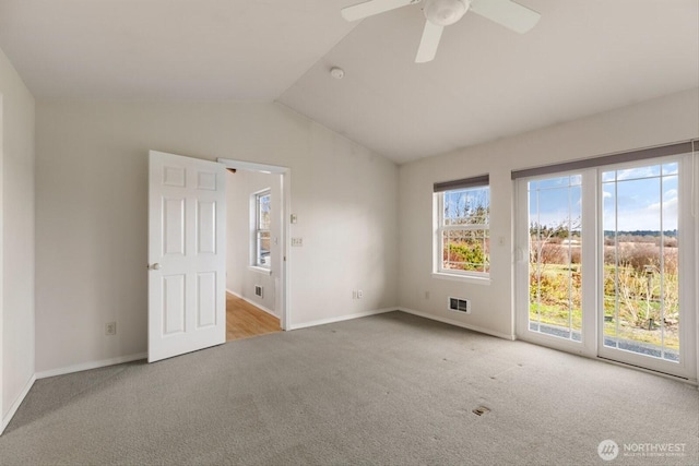 carpeted spare room featuring vaulted ceiling, a ceiling fan, visible vents, and baseboards