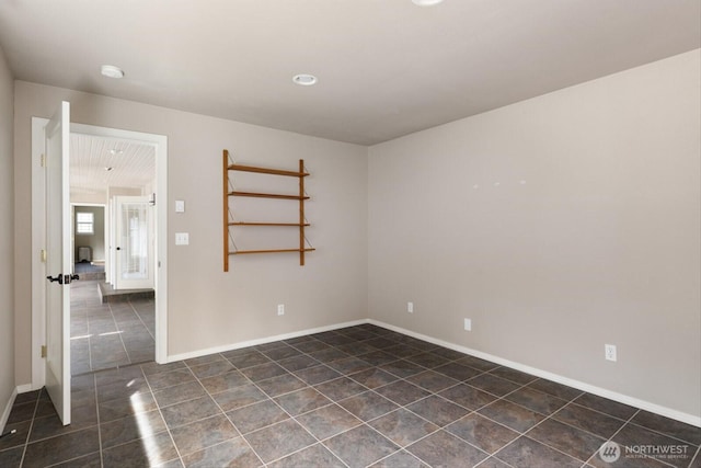 spare room featuring dark tile patterned floors and baseboards