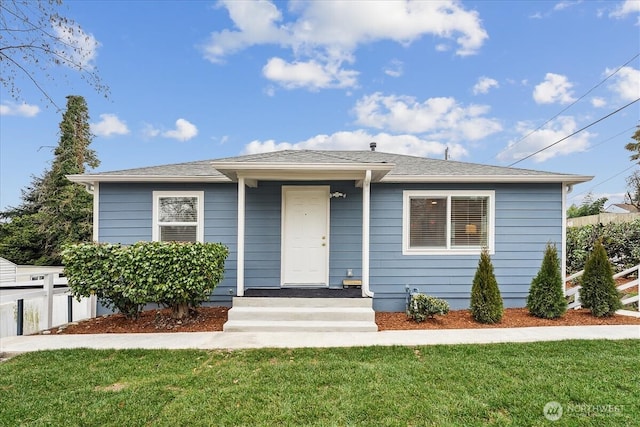 bungalow featuring fence and a front lawn