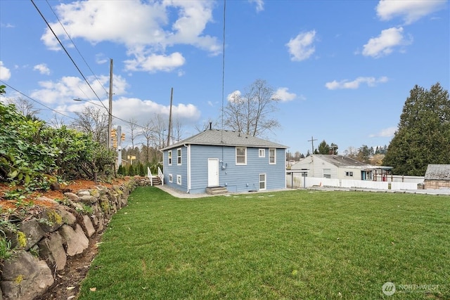 rear view of property featuring entry steps, a yard, and fence