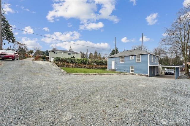 exterior space with an attached carport and gravel driveway