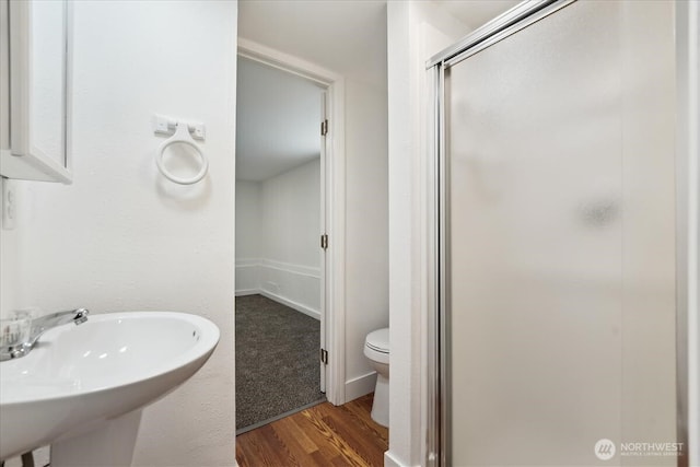 full bath featuring a sink, wood finished floors, toilet, and a shower stall