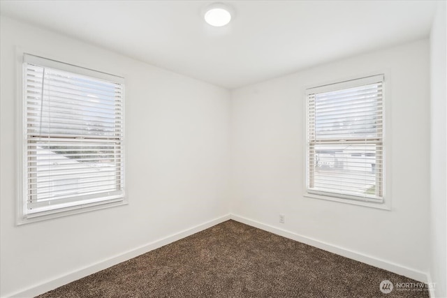 unfurnished room with dark colored carpet and baseboards