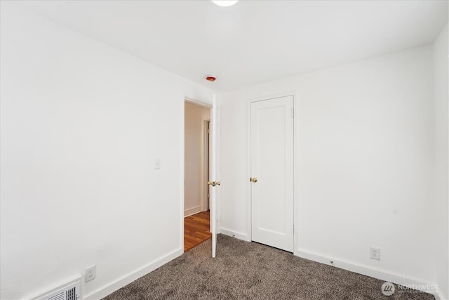 empty room with dark carpet and baseboards