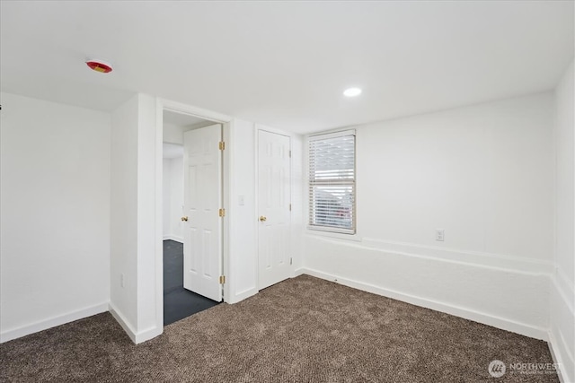 unfurnished bedroom with dark colored carpet and baseboards