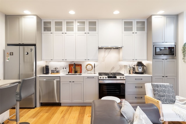 kitchen featuring tasteful backsplash, stainless steel appliances, a sink, and light countertops