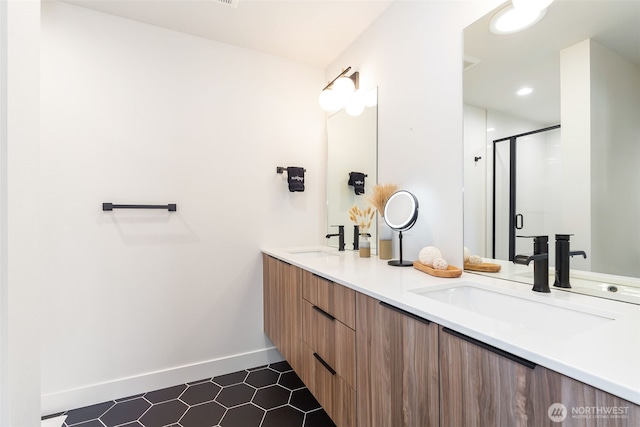 bathroom with double vanity, a stall shower, a sink, and baseboards