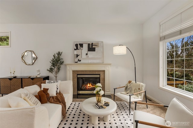 living room featuring a tile fireplace, a healthy amount of sunlight, and baseboards