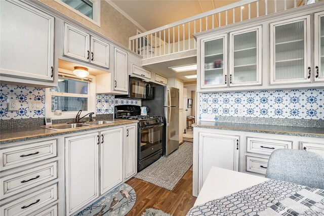 kitchen featuring decorative backsplash, dark wood finished floors, glass insert cabinets, black appliances, and a sink