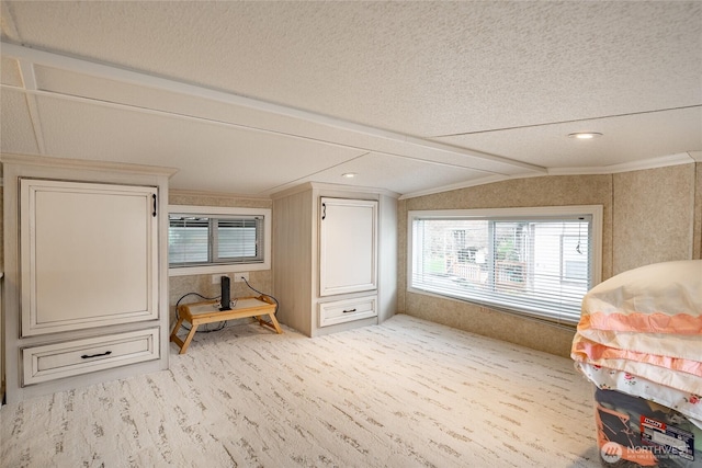 interior space featuring lofted ceiling, a textured ceiling, carpet flooring, and crown molding