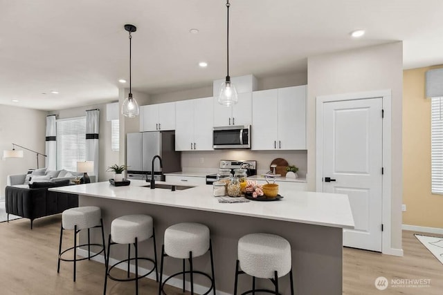 kitchen with stainless steel appliances, a breakfast bar, a sink, and white cabinets