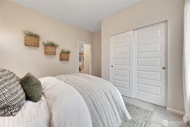 bedroom featuring baseboards, a closet, and light colored carpet