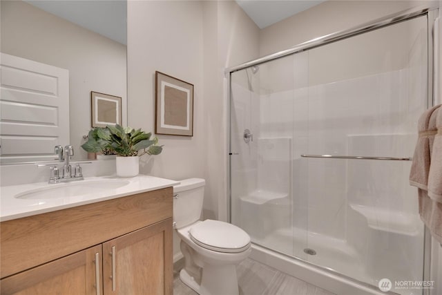 bathroom featuring a stall shower, vanity, and toilet