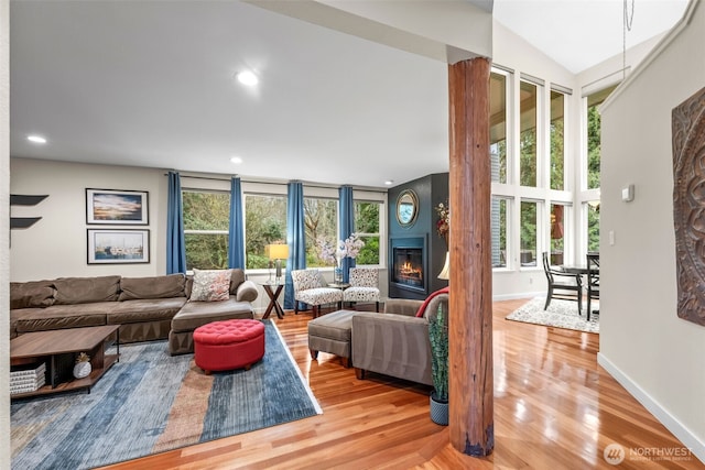 living area with recessed lighting, baseboards, wood finished floors, and a glass covered fireplace