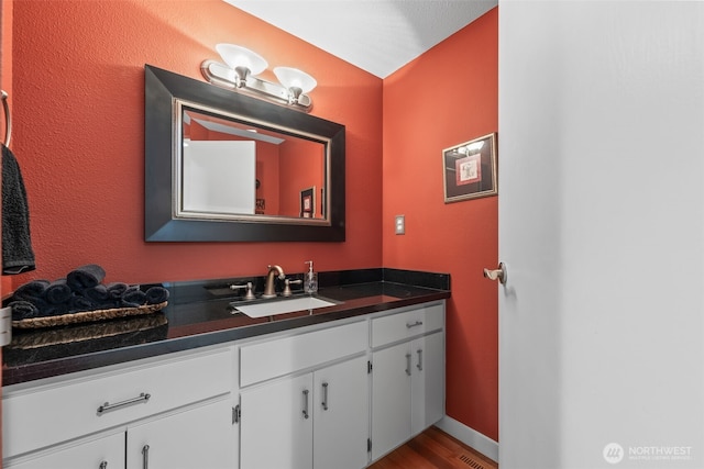 bathroom with baseboards, wood finished floors, and vanity