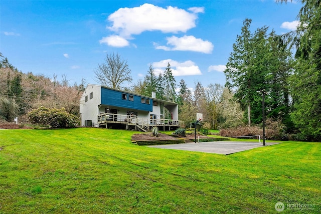 back of house with driveway, a lawn, a wooden deck, and basketball court