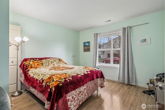 bedroom with visible vents, baseboards, and wood finished floors