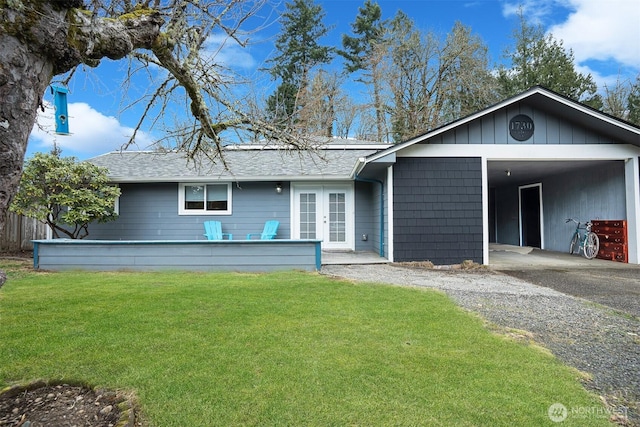 ranch-style house with a front yard, french doors, driveway, and roof with shingles