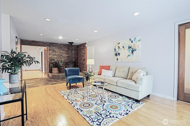 living room with a wood stove, recessed lighting, wood finished floors, and baseboards