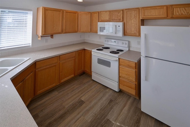 kitchen featuring a sink, white appliances, dark wood finished floors, and light countertops