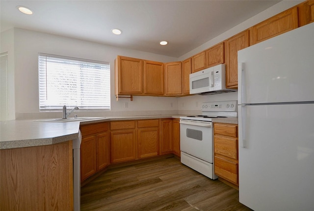 kitchen featuring recessed lighting, light countertops, a sink, wood finished floors, and white appliances