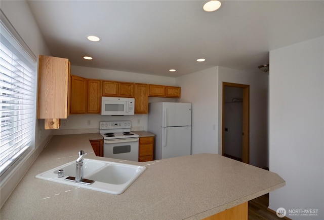 kitchen with a peninsula, white appliances, a sink, and recessed lighting