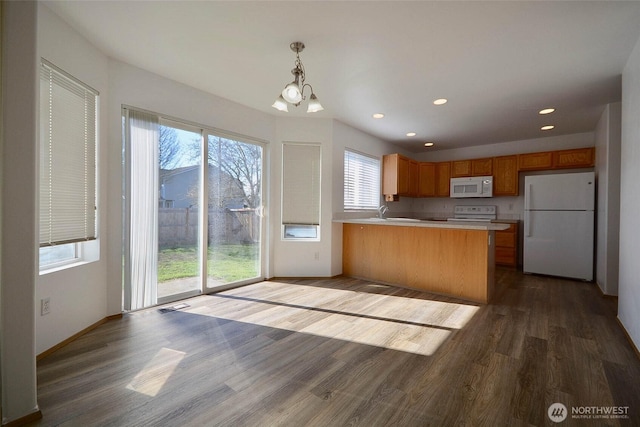 kitchen with light countertops, visible vents, wood finished floors, white appliances, and a peninsula