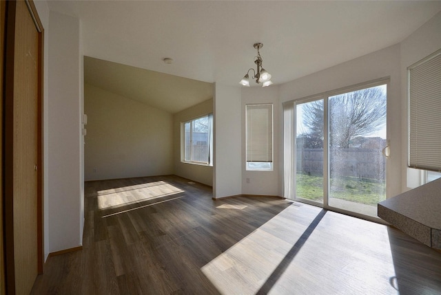 unfurnished dining area with a chandelier, vaulted ceiling, dark wood finished floors, and baseboards