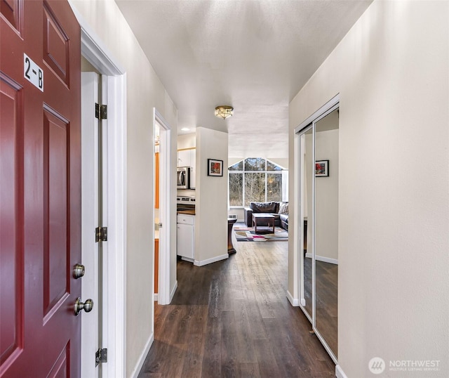 corridor with dark wood-style floors and baseboards