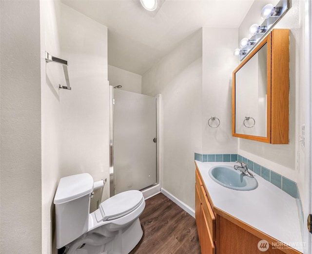 full bath featuring wood finished floors, a shower stall, toilet, and vanity