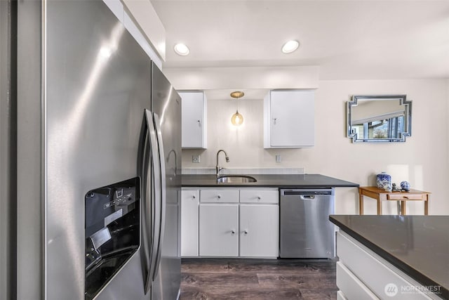 kitchen featuring appliances with stainless steel finishes, dark countertops, white cabinetry, and a sink