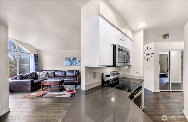 kitchen featuring baseboards, dark wood finished floors, appliances with stainless steel finishes, open floor plan, and white cabinetry