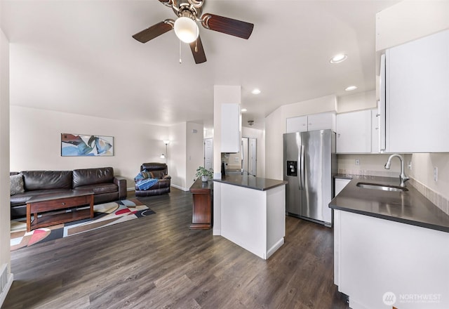 kitchen featuring dark countertops, open floor plan, stainless steel fridge, and a sink