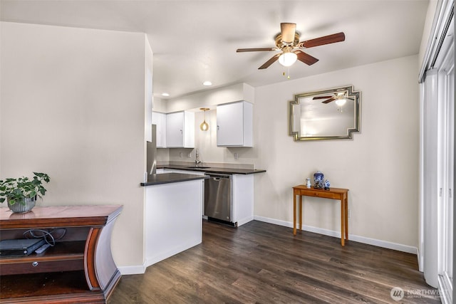 kitchen featuring dark wood finished floors, dark countertops, white cabinets, a sink, and dishwasher