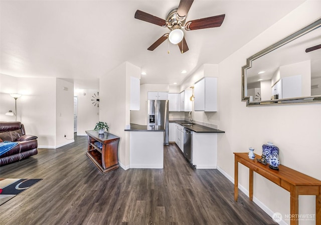 kitchen featuring dark countertops, appliances with stainless steel finishes, open floor plan, dark wood-type flooring, and white cabinetry