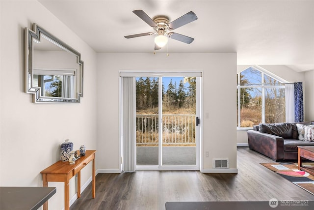 doorway to outside featuring a ceiling fan, visible vents, baseboards, and wood finished floors