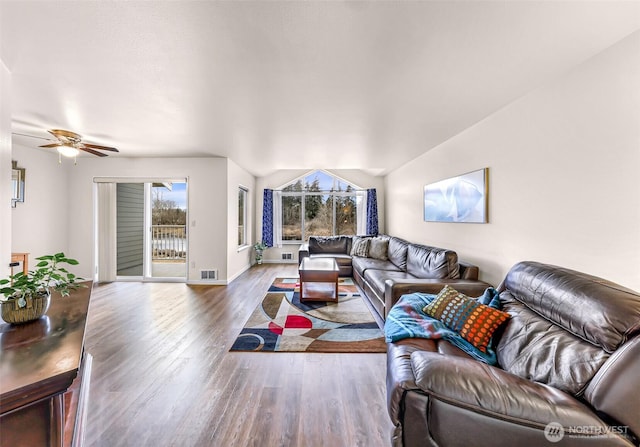 living area featuring baseboards, visible vents, a ceiling fan, wood finished floors, and vaulted ceiling