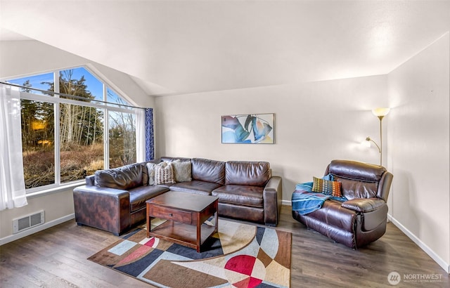 living area with baseboards, visible vents, vaulted ceiling, and wood finished floors