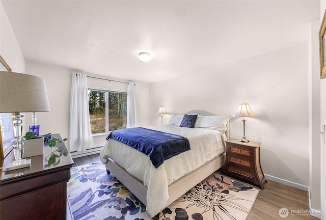 bedroom featuring a baseboard radiator, wood finished floors, and baseboards