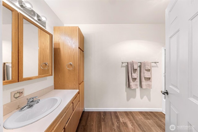 bathroom with baseboards, wood finished floors, and vanity