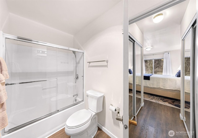 bathroom featuring baseboards, toilet, wood finished floors, ensuite bathroom, and combined bath / shower with glass door